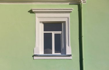 Nane yeşili duvarda güneş ışığında klasik beyaz pencere