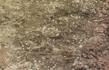 Doğal arka plan kavramları için büyük bir kaya yüzeyinin kaba taş dokusuna yakın çekim. Kirli doğal taştan arkaplan dokusu sıcak tonlarda