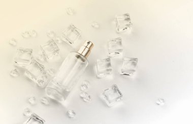 Kadın parfüm şişesi, buz küpleri ve su içinde parfüm şişesinin objektif fotoğrafı. Yukarıdan bak. ürün fotoğrafı, tazelik ve aroma konsepti