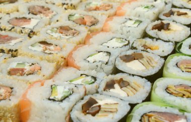 Bir sürü suşi Close-Up farklı dolguları yalanla ahşap yüzeyde alır. Bir kopya alanı ile pişmiş klasik Japon gıda makro çekim.