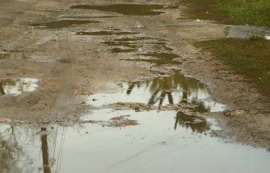 Fotoğraf ile yağmurlu havalarda büyük su birikintileri yok edilen bir yol parçasının