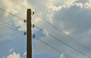 Eski ahşap elektrik direği kablolu elektrik iletimi için bir bulutlu mavi gökyüzü arka plan üzerinde. Daha sonra kullanmak için elektrik temini, eski yöntemi