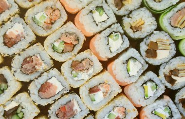 Bir sürü suşi Close-Up farklı dolguları yalanla ahşap yüzeyde alır. Bir kopya alanı ile pişmiş klasik Japon gıda makro çekim.