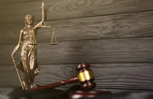The Statue of Justice - lady justice or justitia the Roman goddess of Justice. Statue on brown book with judge gavel. Concept of judicial trial, courtroom process and lawyers occupation