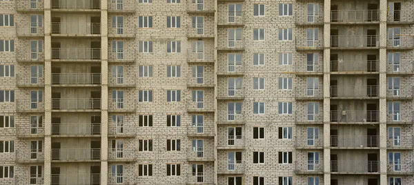 Textured pattern of a russian whitestone residential house building wall with many windows and balcony under construction