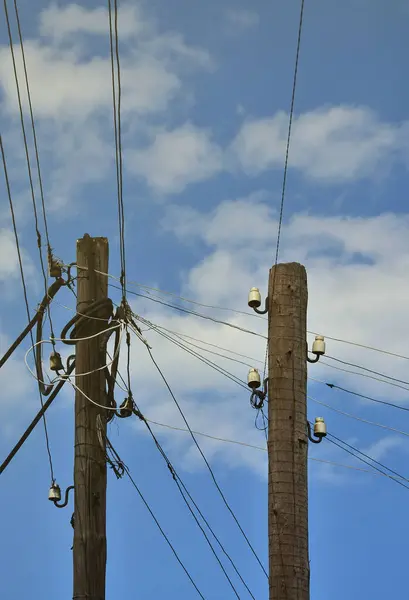 Eski ahşap elektrik direği kablolu elektrik iletimi için bir bulutlu mavi gökyüzü arka plan üzerinde. Daha sonra kullanmak için elektrik temini, eski yöntemi