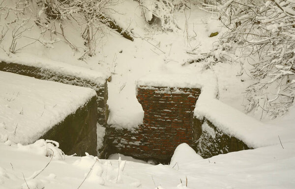 Underground bunker of old brick walls in winter after snowfall
