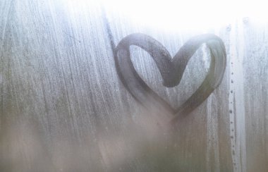 Yağmurlu havalarda misted camına bir parmak tarafından çizilmiş bir kalp şeklinde çizim