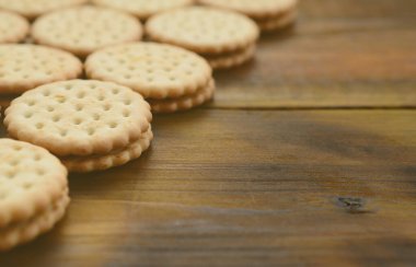 Yuvarlak sandviç kurabiye doldurma Hindistan cevizi ile büyük miktarlarda bir kahverengi ahşap yüzey üzerinde yer almaktadır. Kopya alanı ahşap bir zemin üzerine yemeklik fotoğrafı davranır