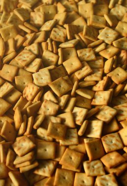 Küçük kurabiye çok kare şeklinde. Sarı tuzlu kraker bir model. Arka plan görüntüsü ile tuzlu pasta