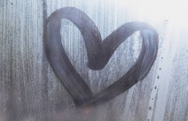 Yağmurlu havalarda misted camına bir parmak tarafından çizilmiş bir kalp şeklinde çizim.