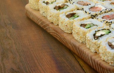 Bir sürü suşi Close-Up farklı dolguları yalanla ahşap yüzeyde alır. Bir kopya alanı ile pişmiş klasik Japon gıda makro çekim.