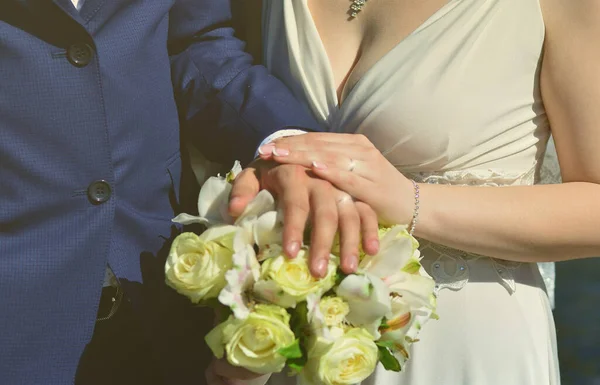 The newlywed couple is holding a beautiful wedding bouquet. Classical wedding photography, symbolizing unity, love and the creation of a new family