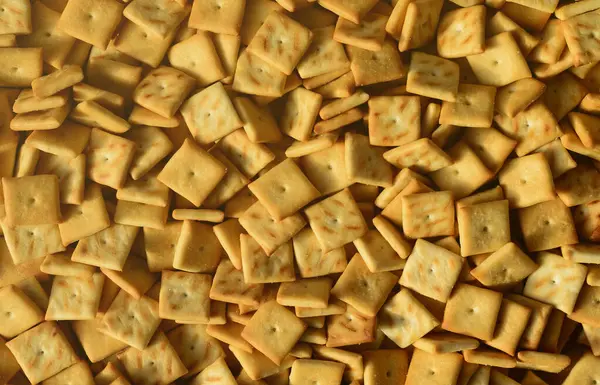 Stock image Background texture of small edible squares baked from dough and sprinkled with salt. A lot of salt cracker