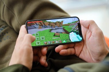 Minecraft mobil iOS oyunu iPhone 15 akıllı telefon ekranında, oyun sırasında erkeklerin elinde. Taşınabilir aygıtta mobil oyun ve eğlence