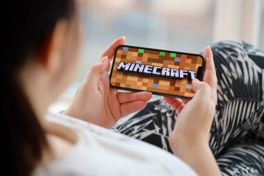 Minecraft mobil iOS oyunu iPhone 15 akıllı telefon ekranında mobil oyun sırasında kadınların elinde. Taşınabilir aygıtta mobil oyun ve eğlence