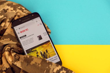 KYIV, UKRAINE - 4 Mayıs 2023: Ukrayna bayrağı ve kamuflaj kumaşı ile Ukrayna haber portalını akıllı telefon ekranına odakla