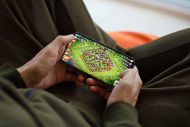 Clash of Clans mobil iOS oyunu iPhone 15 akıllı telefon ekranında, oyun sırasında erkeklerin elinde. Taşınabilir aygıtta mobil oyun ve eğlence