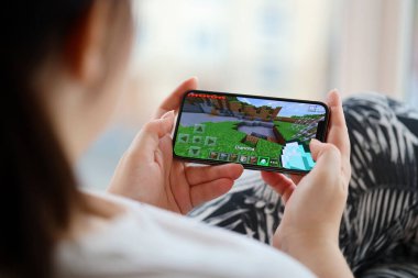 Minecraft mobil iOS oyunu iPhone 15 akıllı telefon ekranında mobil oyun sırasında kadınların elinde. Taşınabilir aygıtta mobil oyun ve eğlence