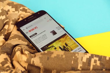 KYIV, UKRAINE - 4 Mayıs 2023: Ukrayna bayrağı ve kamuflaj kumaşı ile Ukrayna haber portalını akıllı telefon ekranına odakla