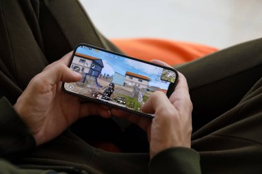 PUBG Bilinmeyen Oyuncular Battleground mobil iOS oyunu iPhone 15 akıllı telefon ekranında cep telefonu oyunu sırasında erkeklerin elinde. Taşınabilir aygıtta mobil oyun ve eğlence