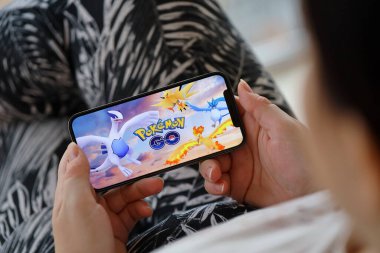 Pokemon GO mobil iOS oyunu iPhone 15 akıllı telefon ekranında mobil oyun sırasında kadınların elinde. Taşınabilir aygıtta mobil oyun ve eğlence