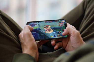 iPhone 15 'teki Kings mobil iOS oyununun onuru cep telefonu oyunu sırasında erkeklerin elinde. Taşınabilir aygıtta mobil oyun ve eğlence