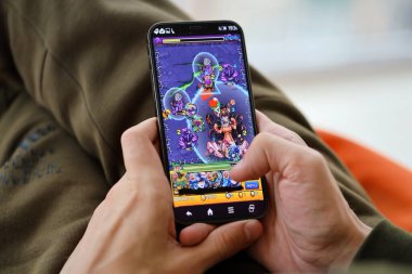 Monster Strike mobil iOS oyunu iPhone 15 akıllı telefon ekranında, oyun sırasında erkeklerin elinde. Taşınabilir aygıtta mobil oyun ve eğlence