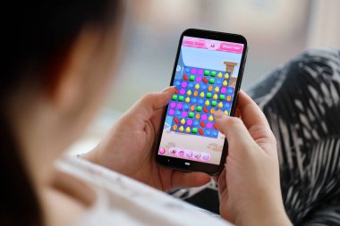 Candy Crush Saga mobil iOS oyunu iPhone 15 akıllı telefon ekranında mobil oyun sırasında kadınların elinde. Taşınabilir aygıtta mobil oyun ve eğlence