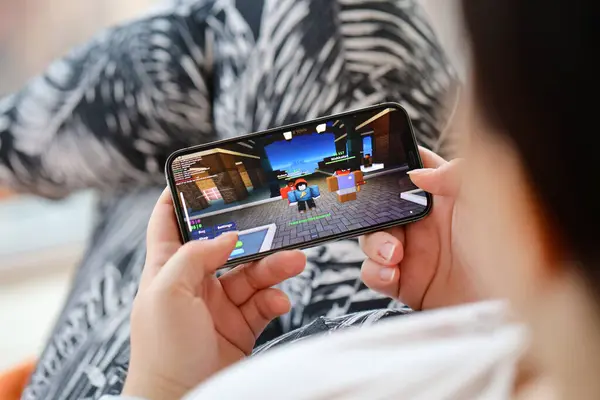 stock image Roblox mobile iOS game on iPhone 15 smartphone screen in female hands during mobile gameplay. Mobile gaming and entertainment on portable device