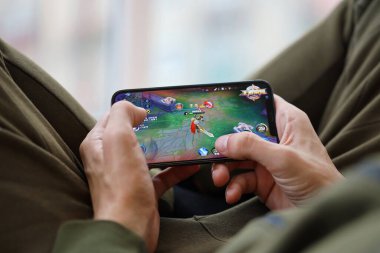 iPhone 15 'teki Kings mobil iOS oyununun onuru cep telefonu oyunu sırasında erkeklerin elinde. Taşınabilir aygıtta mobil oyun ve eğlence
