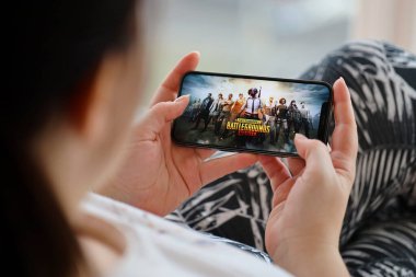 PUBG Bilinmeyen Oyuncular Battleground mobil iOS oyunu iPhone 15 akıllı telefon ekranında mobil oyun sırasında kadınların elinde. Taşınabilir aygıtta mobil oyun ve eğlence