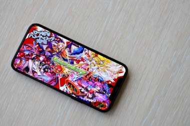 Monster Strike mobil iOS oyunu iPhone 15 akıllı telefon ekranında ahşap masadaki mobil oyun sırasında. Taşınabilir aygıtta mobil oyun ve eğlence