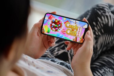 Candy Crush Saga mobil iOS oyunu iPhone 15 akıllı telefon ekranında mobil oyun sırasında kadınların elinde. Taşınabilir aygıtta mobil oyun ve eğlence