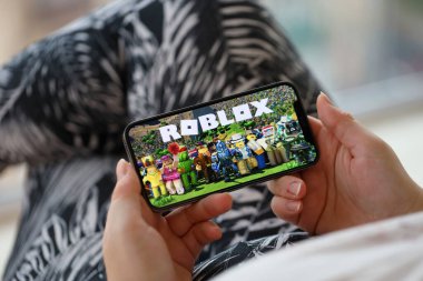 Roblox mobil iOS oyunu iPhone 15 akıllı telefon ekranında mobil oyun sırasında kadınların elinde. Taşınabilir aygıtta mobil oyun ve eğlence