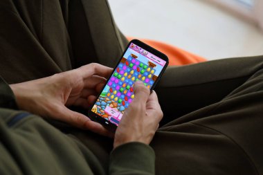 Candy Crush Saga mobil iOS oyunu iPhone 15 akıllı telefon ekranında oyun sırasında erkeklerin elinde. Taşınabilir aygıtta mobil oyun ve eğlence