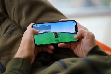 Roblox mobil iOS oyunu iPhone 15 akıllı telefon ekranında, oyun sırasında erkeklerin elinde. Taşınabilir aygıtta mobil oyun ve eğlence