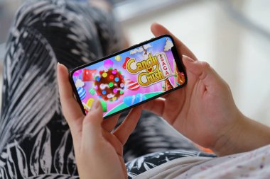 Candy Crush Saga mobil iOS oyunu iPhone 15 akıllı telefon ekranında mobil oyun sırasında kadınların elinde. Taşınabilir aygıtta mobil oyun ve eğlence