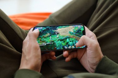 Fantezi Westward Journey mobil iOS oyunu iPhone 15 akıllı telefon ekranında cep telefonu oyunu sırasında erkeklerin elinde. Taşınabilir aygıtta mobil oyun ve eğlence