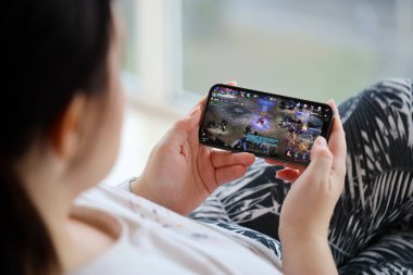Mobil oyun sırasında iPhone 15 akıllı telefon ekranındaki M-Mobil iOS oyunu kadınların elinde. Taşınabilir aygıtta mobil oyun ve eğlence