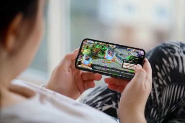 Fantezi Westward Journey mobil iOS oyunu iPhone 15 akıllı telefon ekranında mobil oyun sırasında kadınların elinde. Taşınabilir aygıtta mobil oyun ve eğlence
