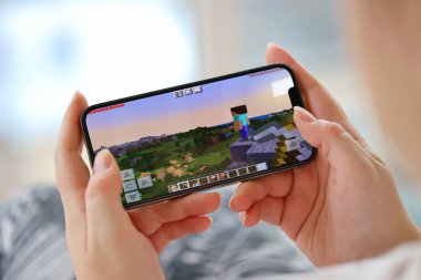 Minecraft mobil iOS oyunu iPhone 15 akıllı telefon ekranında mobil oyun sırasında kadınların elinde. Taşınabilir aygıtta mobil oyun ve eğlence