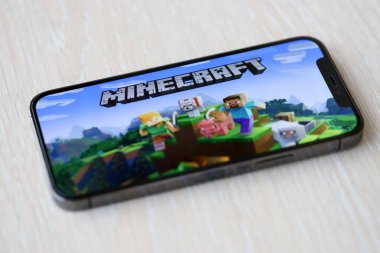 Minecraft mobil iOS oyunu iPhone 15 akıllı telefon ekranında ahşap masadaki mobil oyun sırasında. Taşınabilir aygıtta mobil oyun ve eğlence