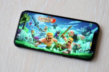 Clash of Clans mobil iOS oyunu iPhone 15 akıllı telefon ekranında ahşap masadaki mobil oyun sırasında. Taşınabilir aygıtta mobil oyun ve eğlence