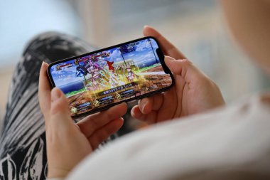 Kader, iPhone 15 akıllı telefon ekranındaki iOS mobil oyun sırasında kadınların elindeydi. Taşınabilir aygıtta mobil oyun ve eğlence