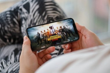 PUBG Bilinmeyen Oyuncular Battleground mobil iOS oyunu iPhone 15 akıllı telefon ekranında mobil oyun sırasında kadınların elinde. Taşınabilir aygıtta mobil oyun ve eğlence