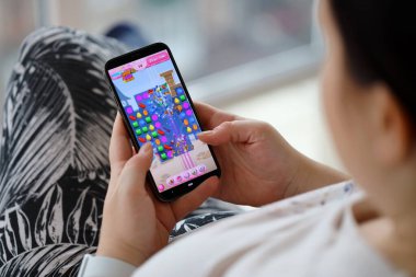 Candy Crush Saga mobil iOS oyunu iPhone 15 akıllı telefon ekranında mobil oyun sırasında kadınların elinde. Taşınabilir aygıtta mobil oyun ve eğlence