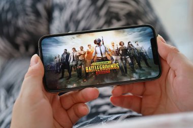 PUBG Bilinmeyen Oyuncular Battleground mobil iOS oyunu iPhone 15 akıllı telefon ekranında mobil oyun sırasında kadınların elinde. Taşınabilir aygıtta mobil oyun ve eğlence