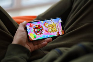 Candy Crush Saga mobil iOS oyunu iPhone 15 akıllı telefon ekranında oyun sırasında erkeklerin elinde. Taşınabilir aygıtta mobil oyun ve eğlence