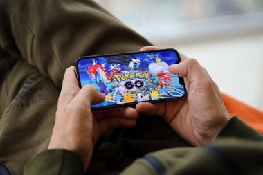 Pokemon GO mobil iOS oyunu iPhone 15 akıllı telefon ekranında oyun sırasında erkeklerin elinde. Taşınabilir aygıtta mobil oyun ve eğlence